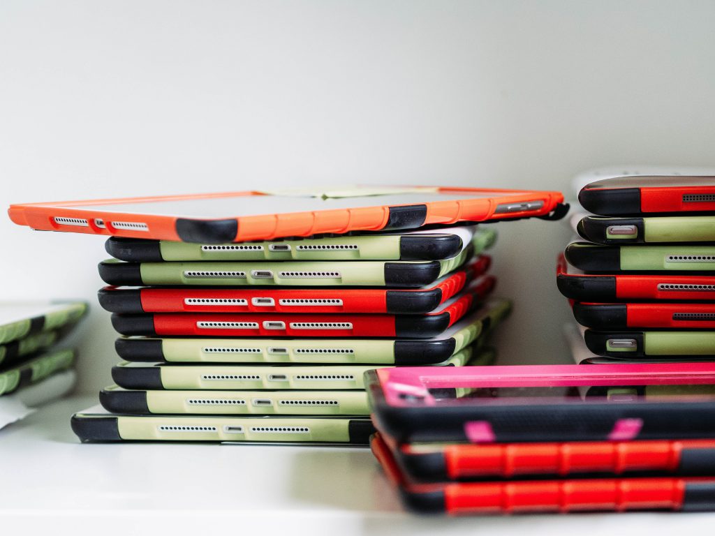 A stack of iPads with brightly coloured cases for use in school