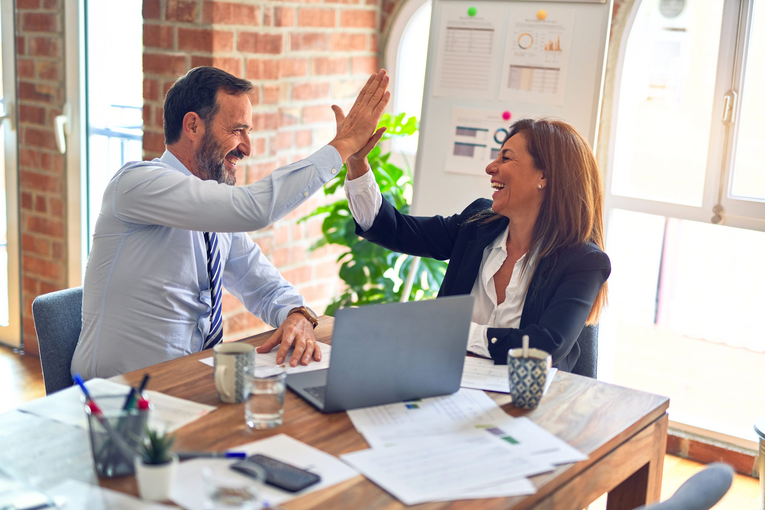 Two business managers high five and smile as they find their perfect leasing solution