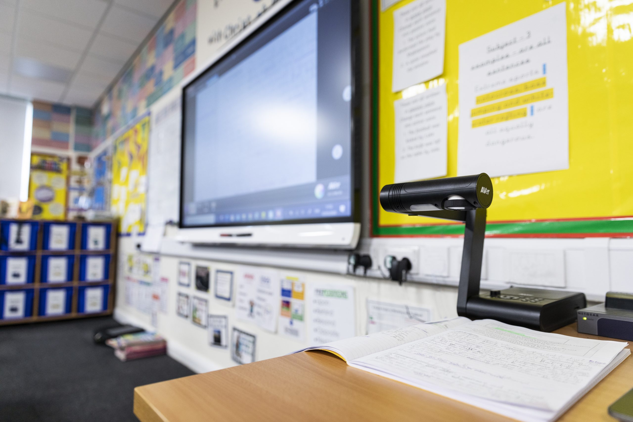 The front of a primary school classroom showing an interactive touchscreen board and a visualiser.