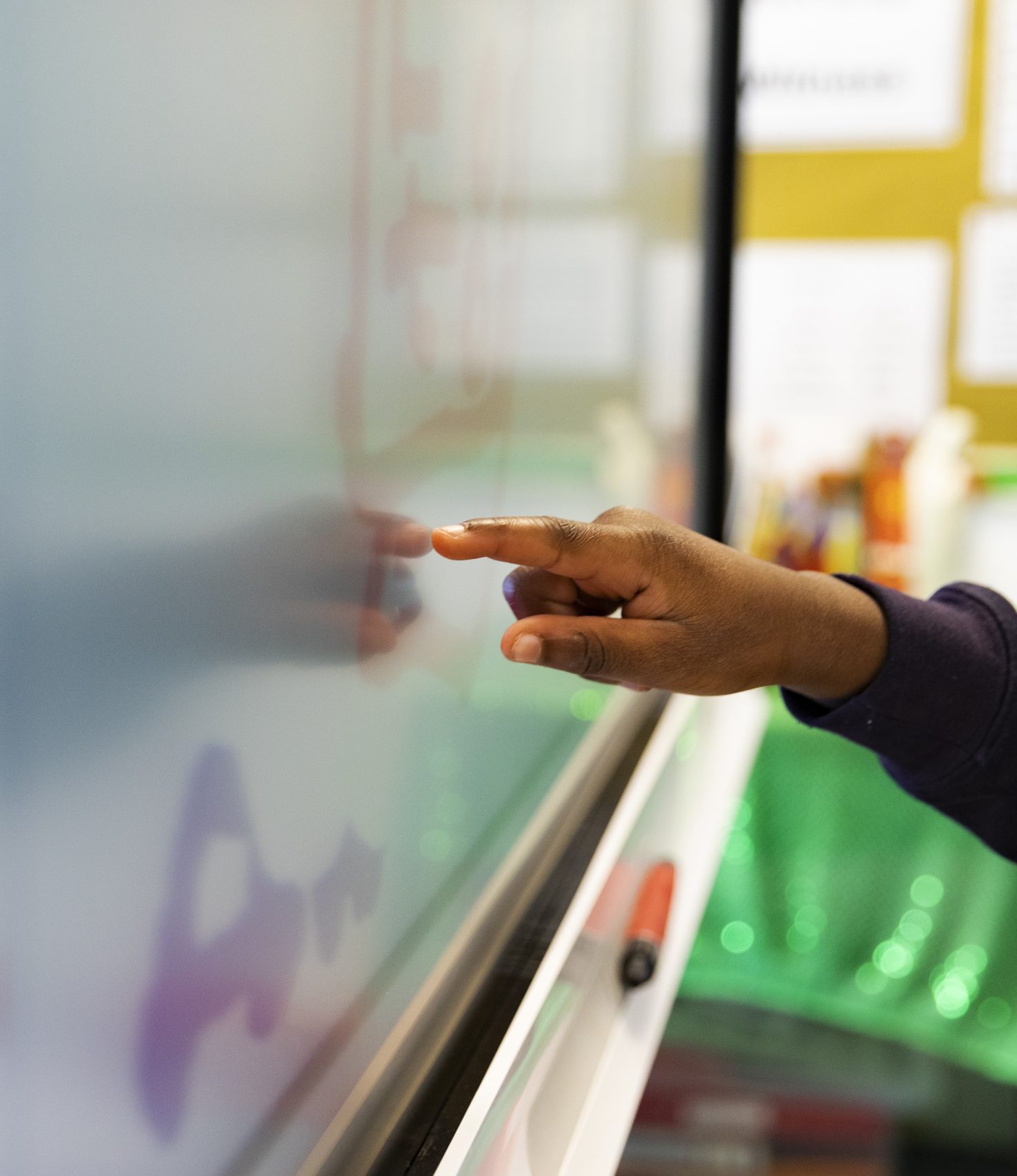 A pupil draws on an interactive touchscreen board in a classroom.