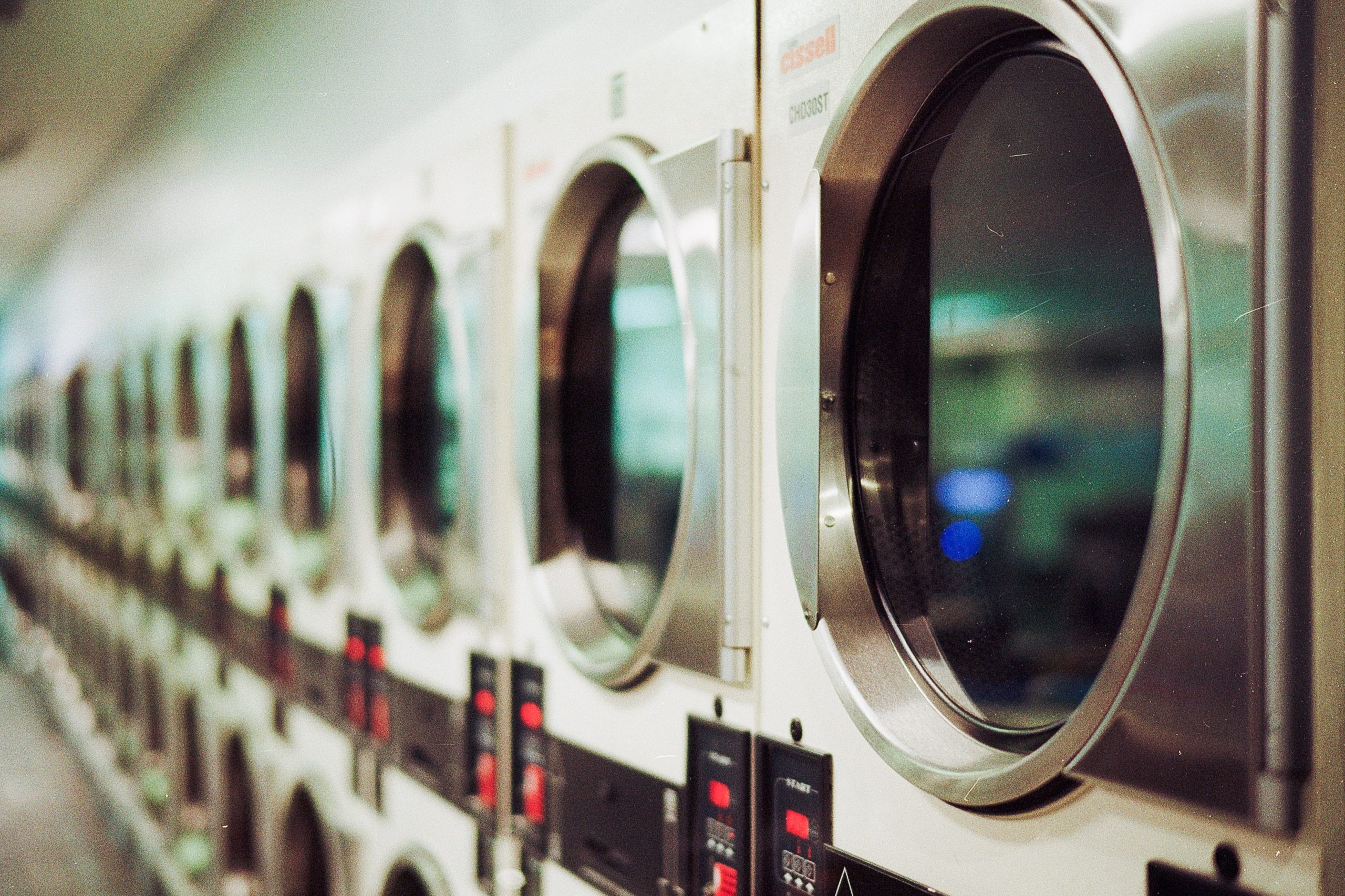 A line of school laundry equipment including washing machines and dryers.