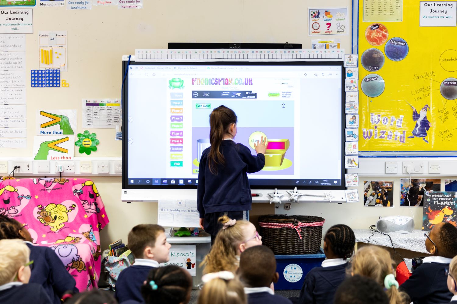 Pupil using interactive touchscreen board in a classroom