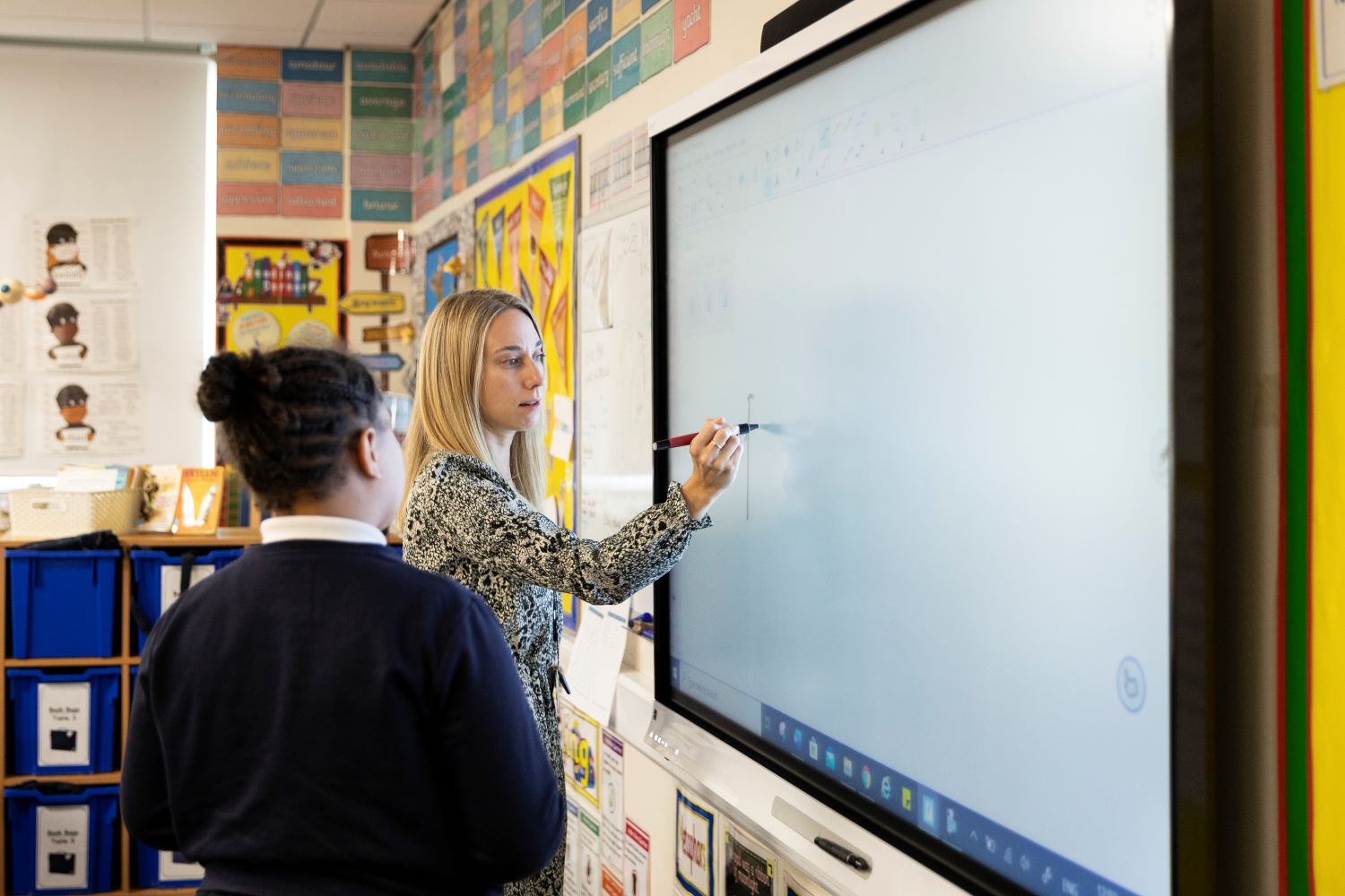 Teacher demonstrating how to solve a problem on an interactive touchscreen board
